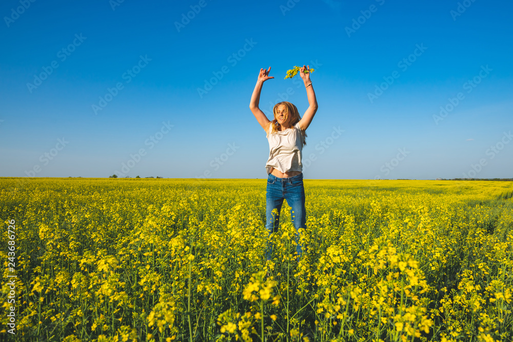 Joyful beautiful woman blonde, with open arms, jumps on the field Joyful beautiful woman blonde, with open arms, jumps on the field