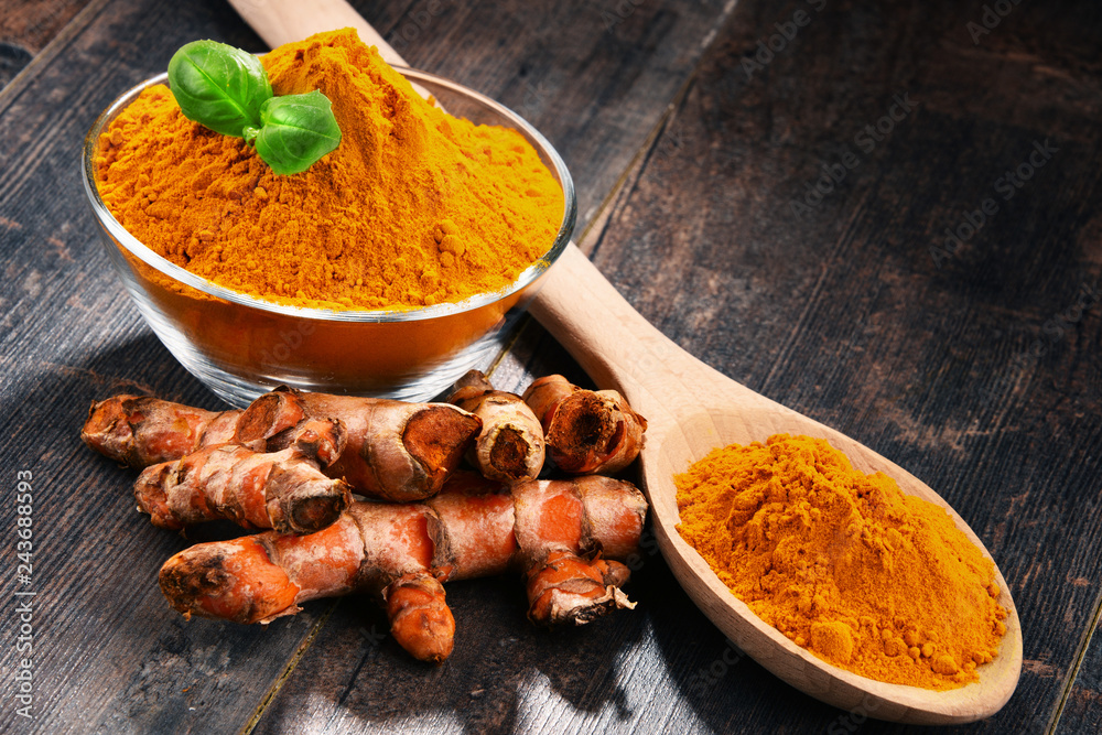 Composition with bowl of turmeric powder on wooden table Composition with bowl of turmeric powder on wooden table