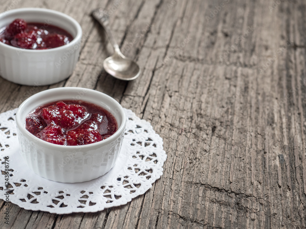 Homemade strawberry sweet tasty jam with whole berries on wooden background Homemade strawberry sweet tasty jam with whole berries on wooden background
