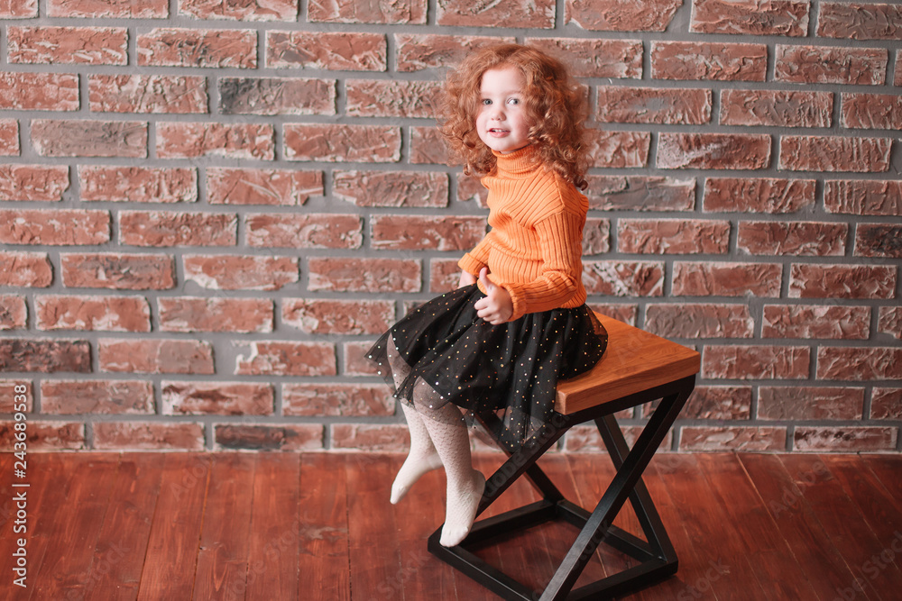 cute little girl sitting on a chair in a new living room.