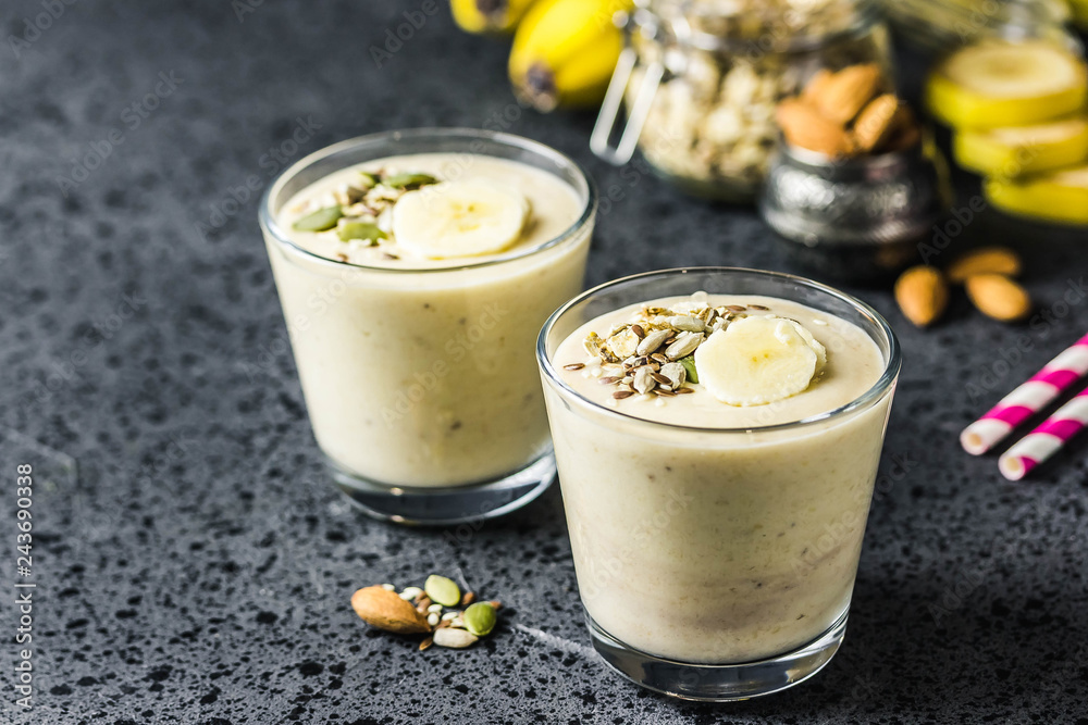 Oats banana almond milk shake with nuts and seeds on dark background. Selective focus, space for text. Oats banana almond milk shake with nuts and seeds on dark background. Selective focus, space for text.