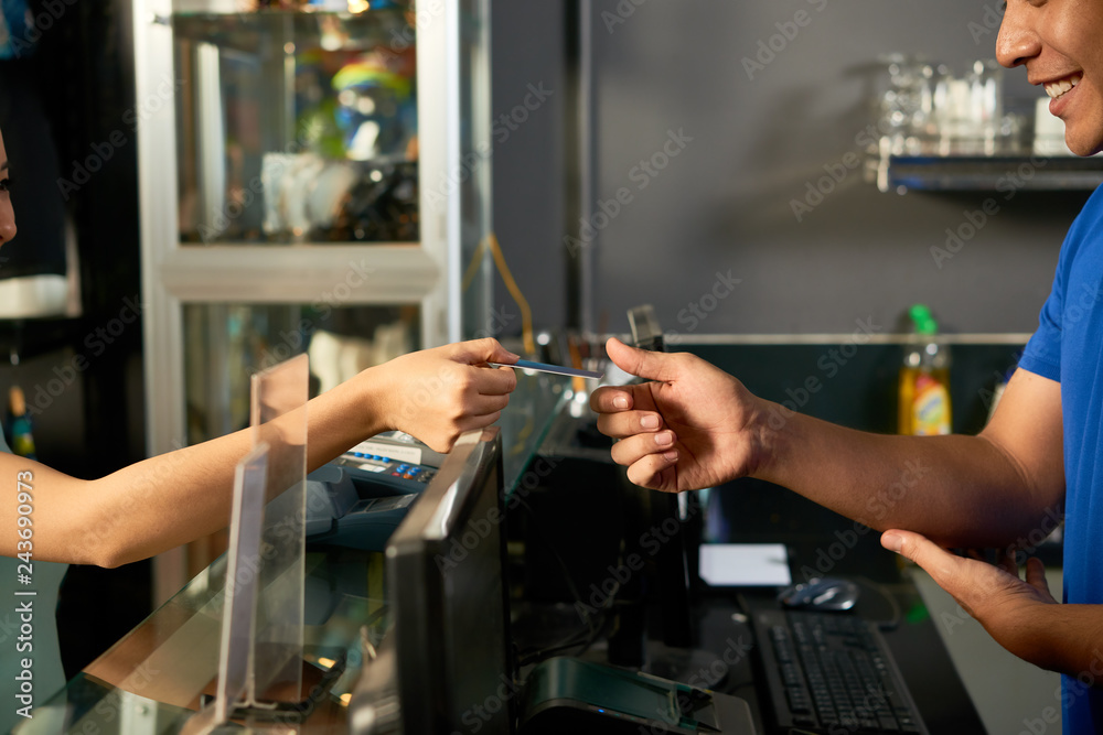 Female customer giving credit card to cashier to pay for purchases