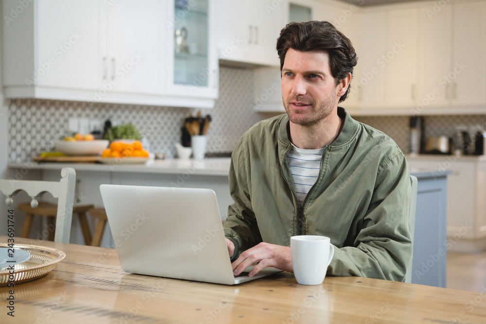 Man using laptop in kitchen Man using laptop in kitchen