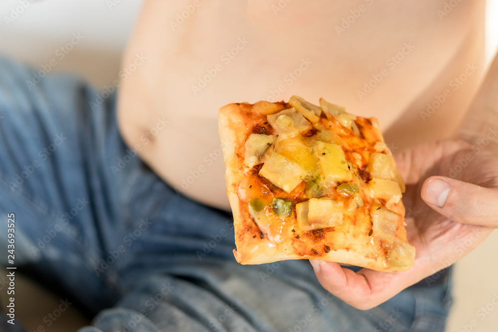 Unhealthy fat young man holding pizza fast food.