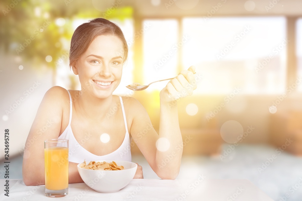 Attractive smiling young woman having breakfast on kitchen