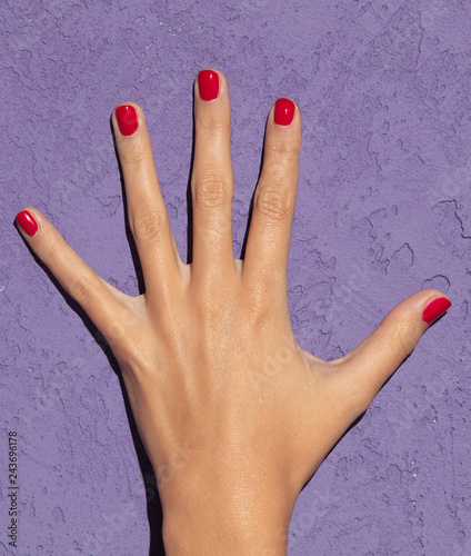 Hands with red nails on magenta background