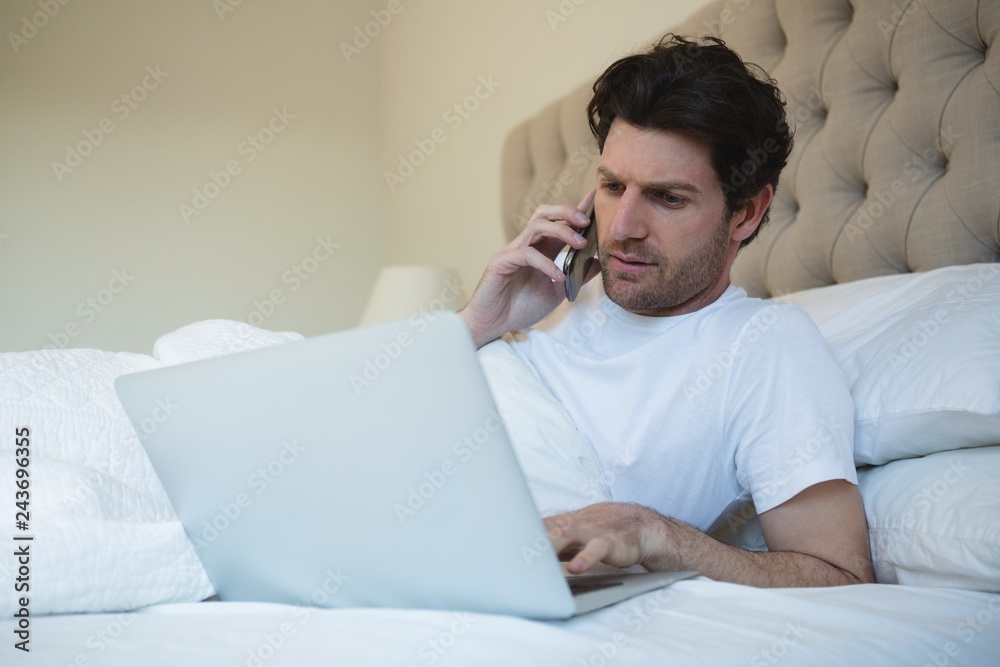 Man using laptop while talking on mobile phone Man using laptop while talking on mobile phone