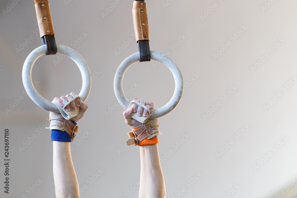 Sportsman hands with grips on gymnastic rings
