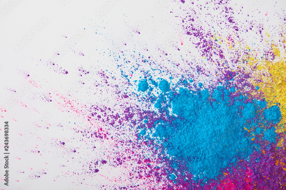 top view of explosion of yellow, purple and blue holi powder on white background top view of explosion of yellow, purple and blue holi powder on white background