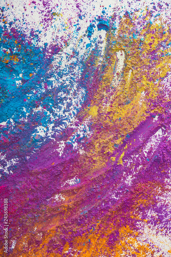 top view of yellow, purple, orange and blue holi powder on white background