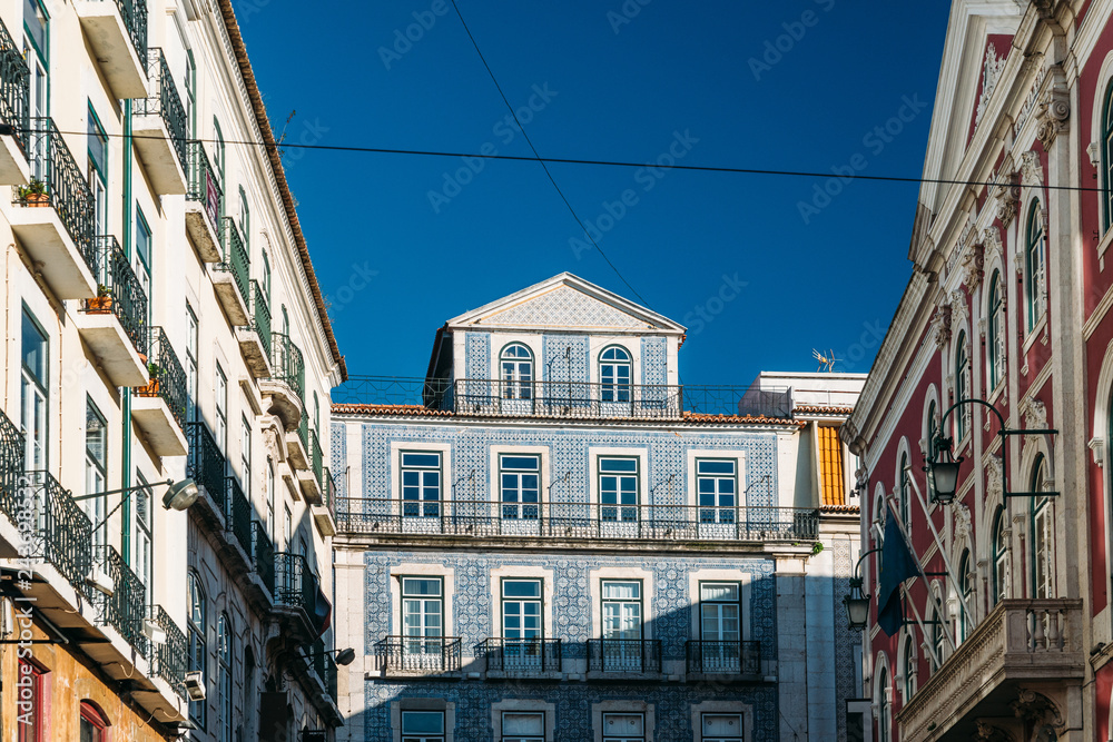 Traditional Portugal house facade with doors, windows and balcony. Blue azulejos tiled building wall in Lisbon