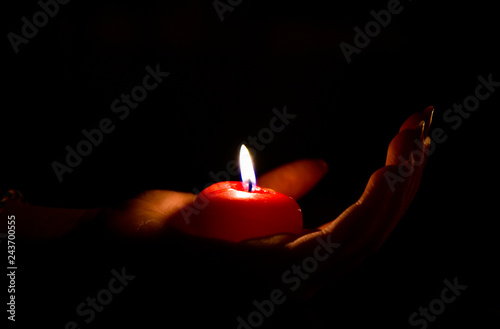 Red burning candle lying on a woman's hand