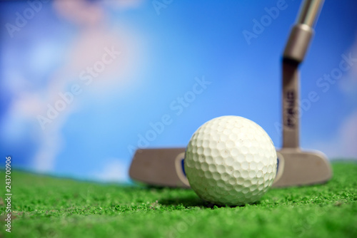 Golf club and golf ball on tee in grass