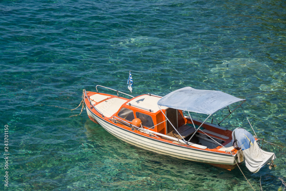 Small white brown wooden motorized boat anchored on the shore