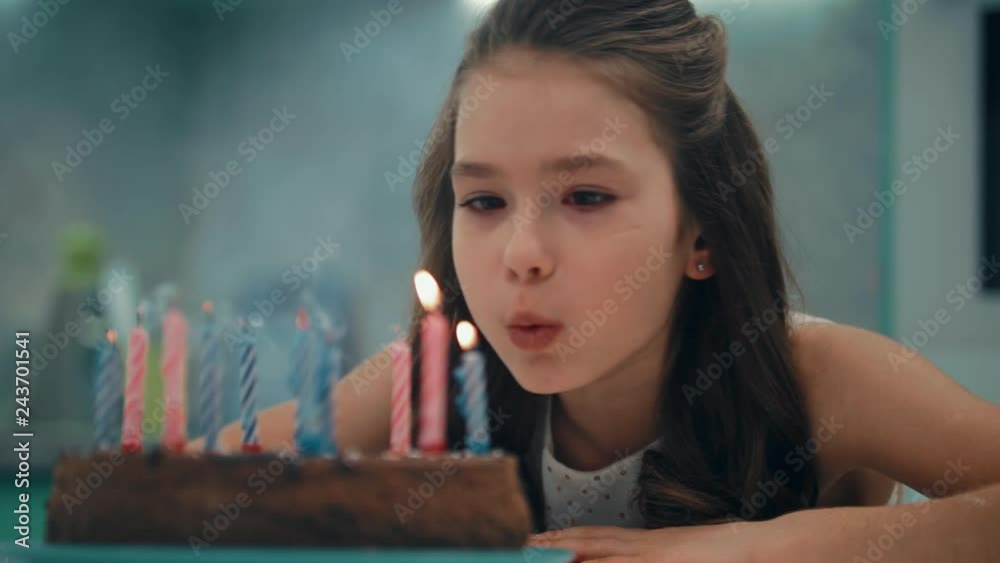 Portrait of girl blowing candles in slow motion. Child happy birthday concept