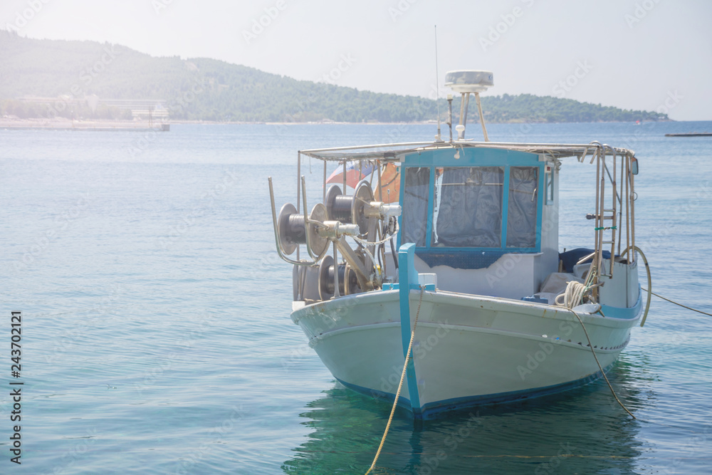 Small white overloaded fishing boat anchored next to the dock Small white overloaded fishing boat anchored next to the dock