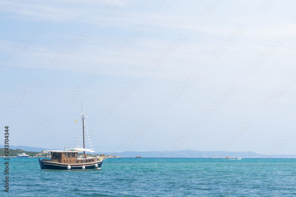 Brown blue wooden boat sails in the sea