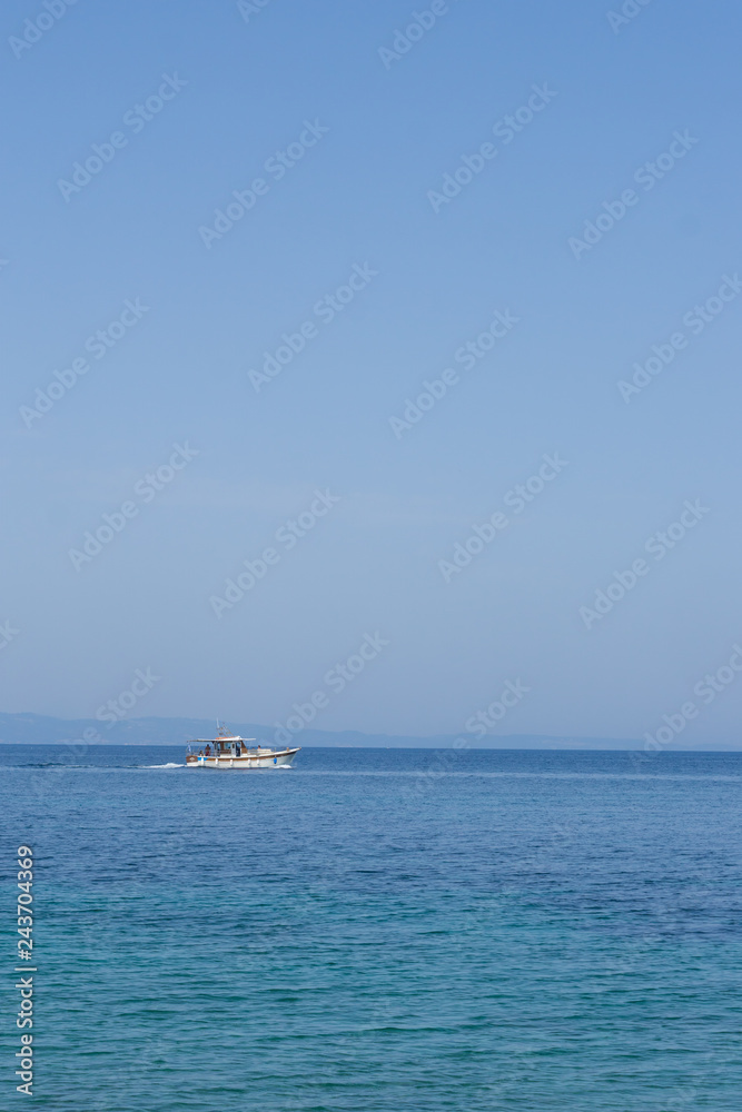 Small white motorized boat with one man sails in the open sea