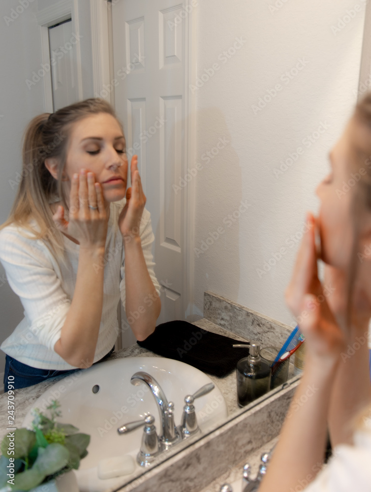 Beautiful Young Woman Looking and Examining Her Face and Makeup in Her Home Bathroom Mirror in the Morning Getting Ready for a Good Day Beautiful Young Woman Looking and Examining Her Face and Makeup in Her Home Bathroom Mirror in the Morning Getting Ready for a Good Day