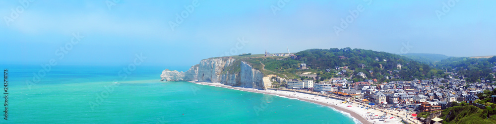 Picturesque panoramic landscape of famous village Etretat, Normandy. Natural cliff and beach. French seaside resort, visitors and tourists. Coast of the Pays de Caux area in sunny summer day