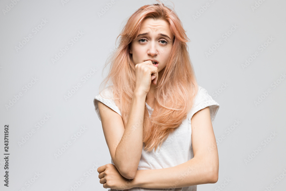 Cropped studio portrait of cute blonde girl in white t-shirt looks with bewilderment and disappointment/closed posture, angry, strict and skeptical expression, negative emotion, destruct. Cropped studio portrait of cute blonde girl in white t-shirt looks with bewilderment and disappointment/closed posture, angry, strict and skeptical expression, negative emotion, destruct.