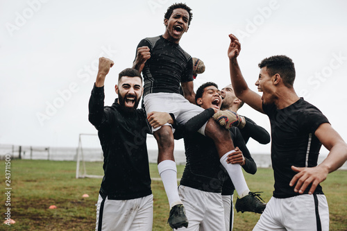 Fototapeta Naklejka Na Ścianę i Meble -  Soccer players celebrating success by lifting a teammate on shou