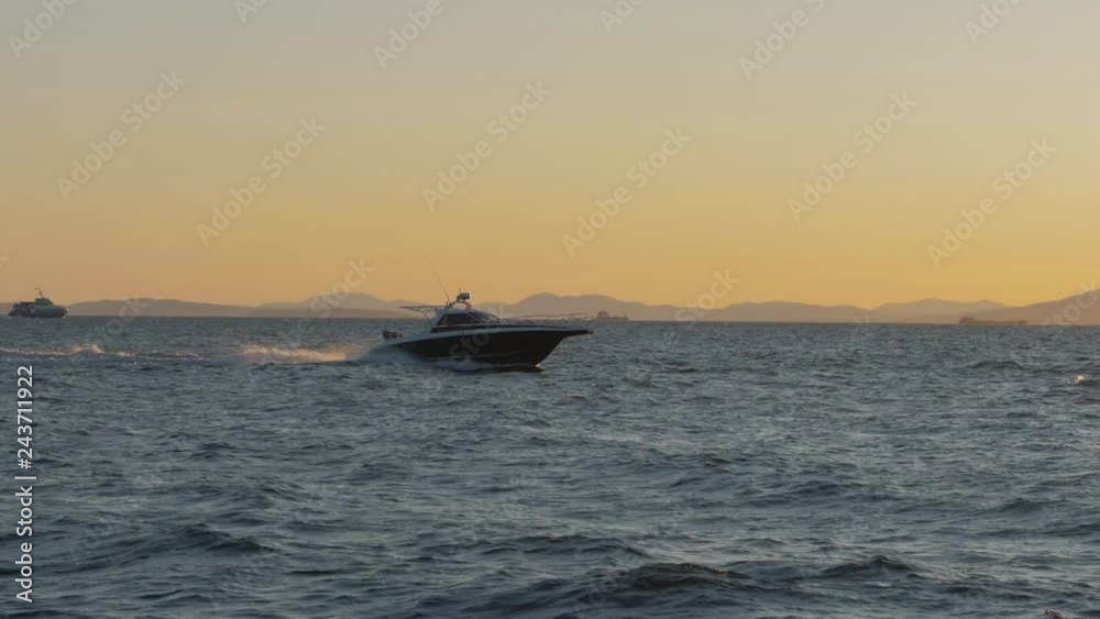 Black and white private motor yacht in the sea on sunset