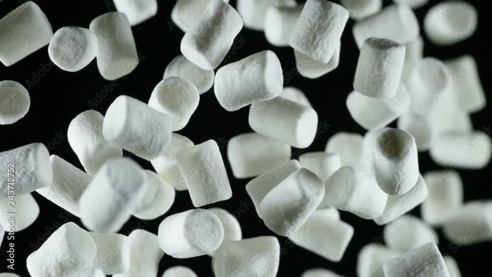 Soft Marshmallow Planted Up. A large number of light marshmallow flies into the frame of the darkness. Filmed at a speed of 480fps
