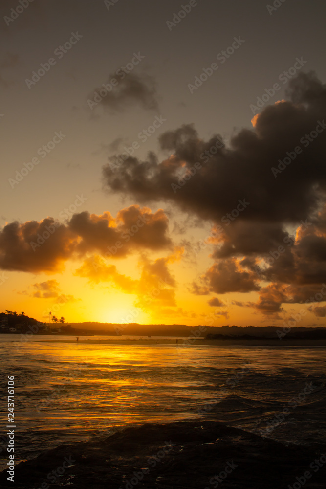 Fototapeta premium Dawn on the coast, the sun dyes the clouds of golden colors.