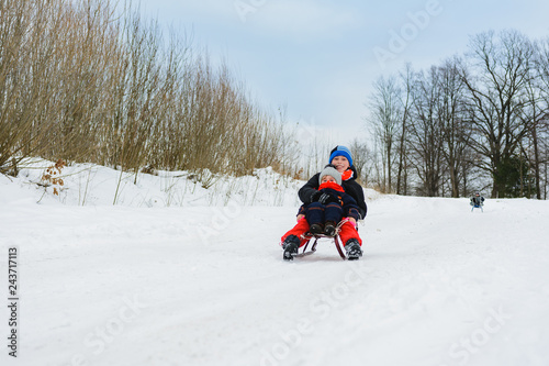 boy and girl are riding on sleds