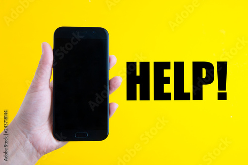 Help word, letering. Hand holding a modern smartphone over yellow. Comunication and services. photo