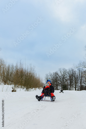 children on two sledges descend from the hills
