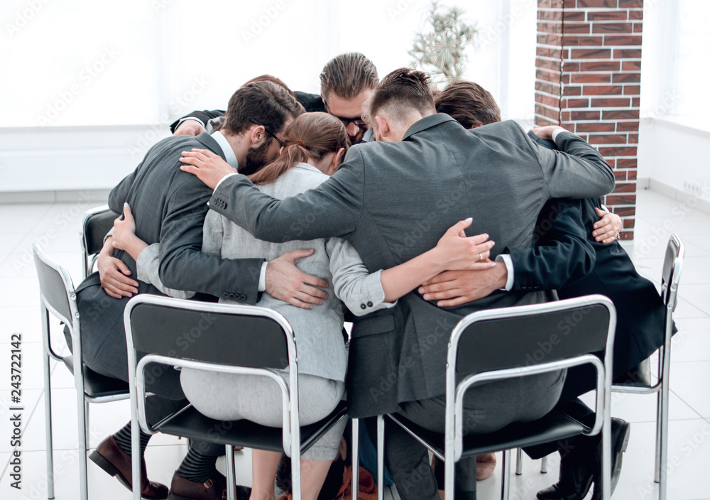 Fototapeta premium business team sits in a circle and hugs each other