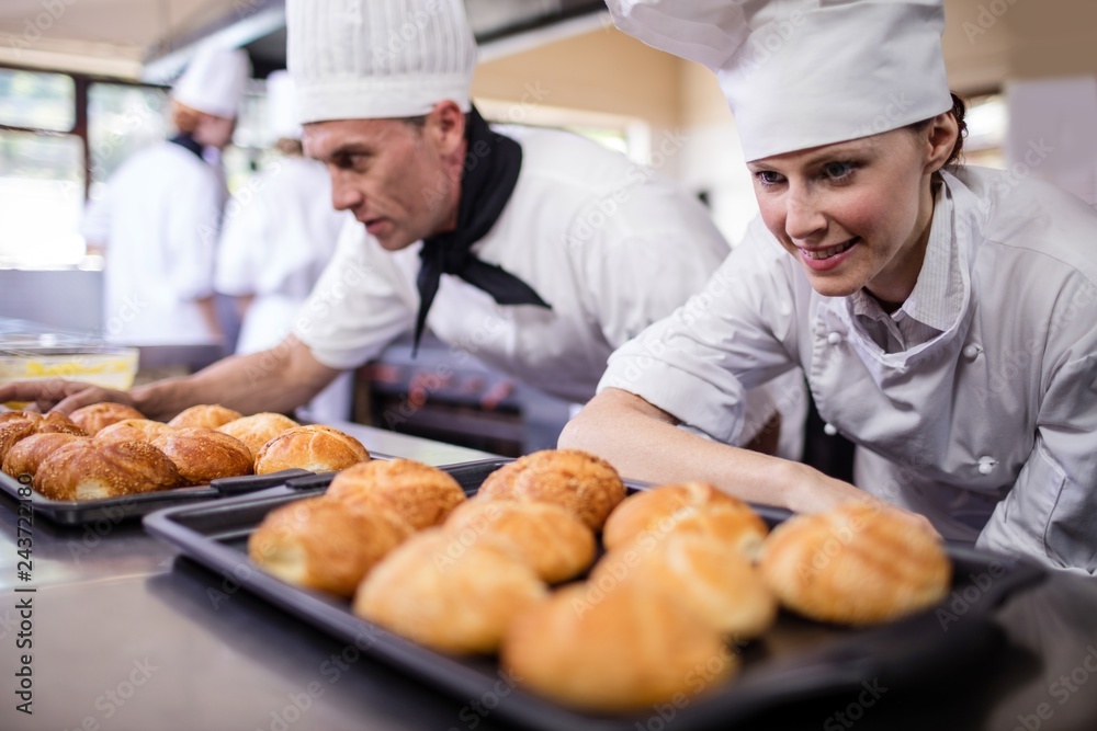 Male and female chefs preparing kaiser rolls in kitchen Male and female chefs preparing kaiser rolls in kitchen