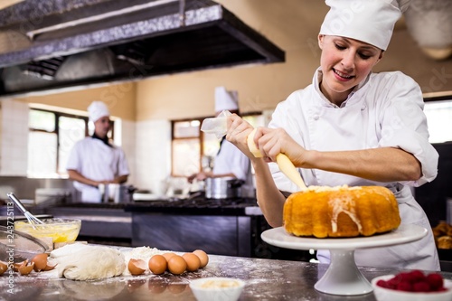 Fototapeta Naklejka Na Ścianę i Meble -  Female chef piping a cake in kitchen