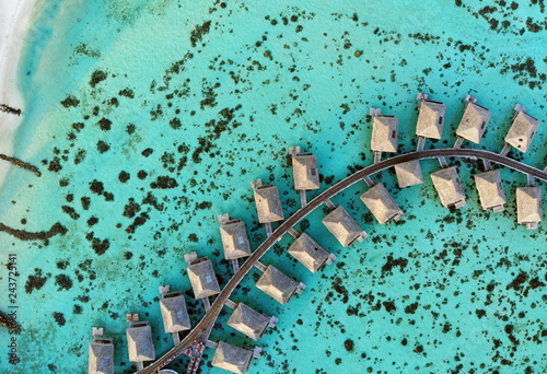 Aerial view of overwater bungalows with thatched roofs in the Moorea lagoon in French Polynesia
