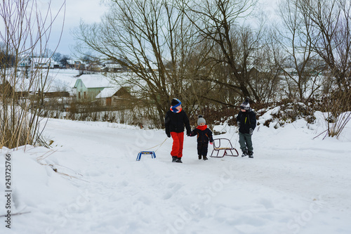 Three children are dragging sleigh in the mountain