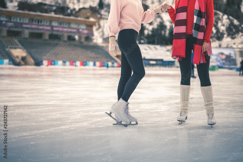 Unrecognizable teenagers girls ice skating outdoor at ice rink