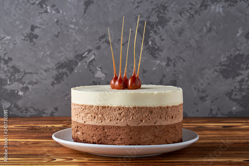 Three chocolate mousse cake. Festive dessert, chocolate pie on white bowl. Hazelnut in caramel decorated on top