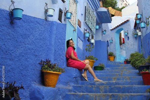 Beautiful Moroccan girl in pink dress against blue city background © James