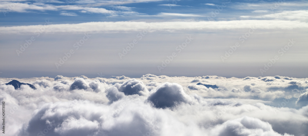 Panoramic view on snowy mountains covered with beautiful sunlight clouds