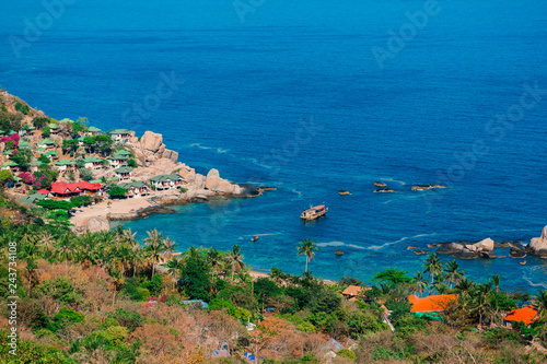  Scenic aerial view of Shark Bay (Haad Tien Bay) on Koh Tao island, Thailand, with turquoise waters, traditional longtail boat, palm trees, and lush tropical coastline. Idyllic vacation destination