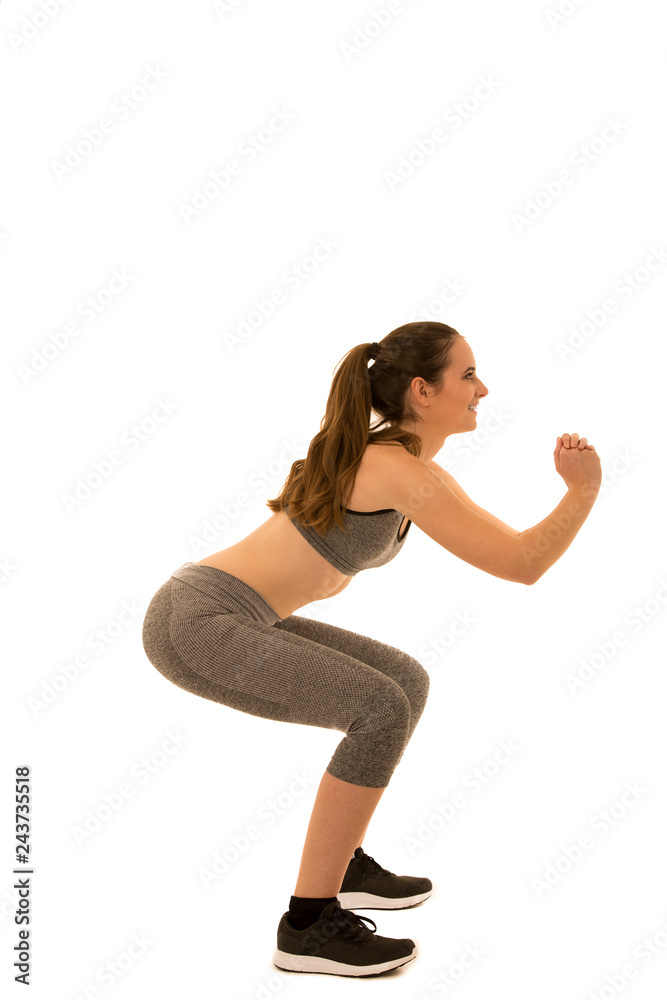 Beautiful young fit woman makes squats isolated over white background