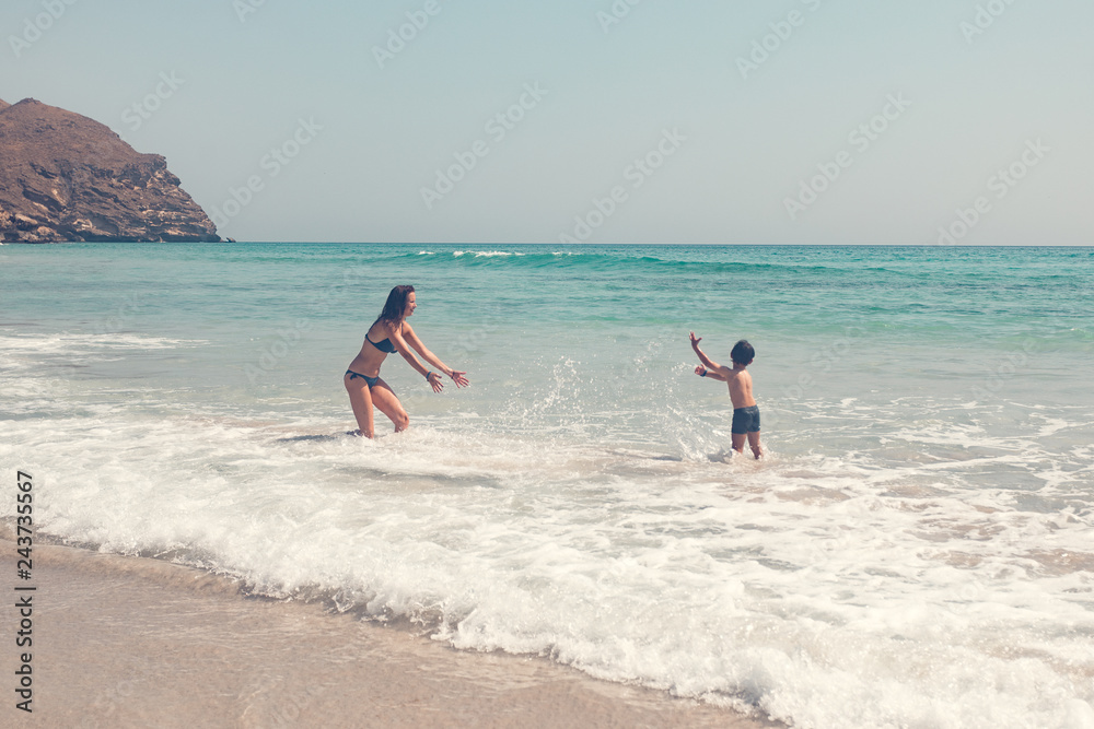 mother and son splashing water in the sea mother and son splashing water in the sea