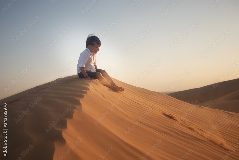 boy sitting on the sand dune