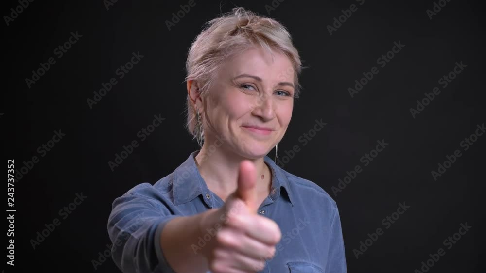 Closeup portrait of attractive middle-aged female showing thumb up and smiling looking at camera Closeup portrait of attractive middle-aged female showing thumb up and smiling looking at camera