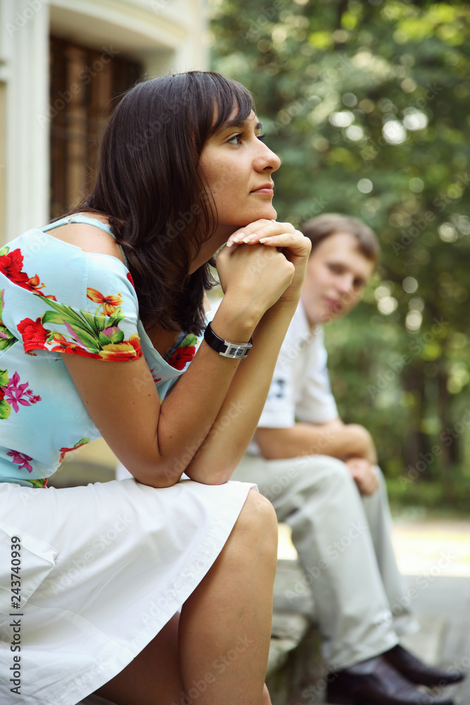 Obraz premium Young woman and man sitting on marble steps in park, selective focus