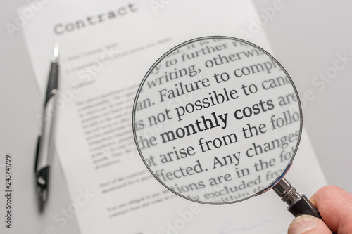 Contract is checked with a magnifying glass on the subject of monthly costs as a result of a contract photo