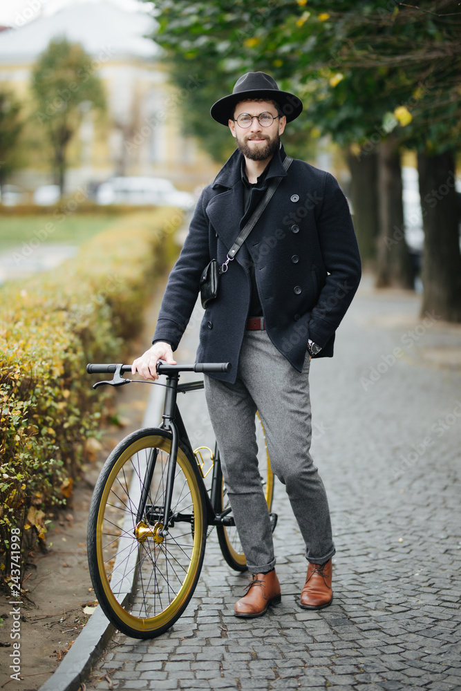Enjoying the urban lifestyle. Young bearded man while sitting on his bicycle outdoors