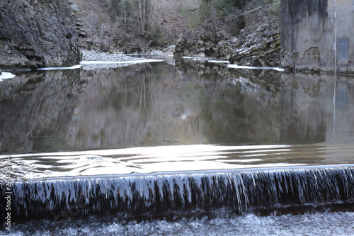 A small waterfall over concrete in the Veral river with grey rock and cold ice stalactites in the Foz de Binies zone, during winter, in Aragon, Spain photo